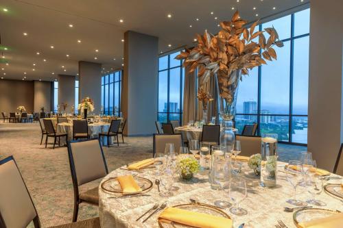 uma sala de jantar com mesas e cadeiras e janelas grandes em Hilton San Jose La Sabana em San José
