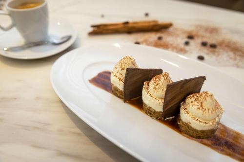 a white plate with desserts and a cup of coffee at Hilton San Jose La Sabana in San José