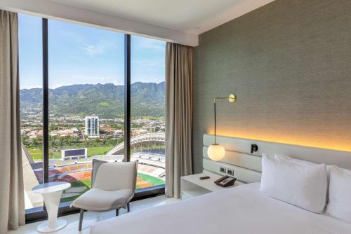 a hotel room with a bed and a large window at Hilton San Jose La Sabana in San José