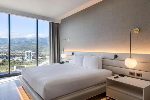 a bedroom with a large bed with a large window at Hilton San Jose La Sabana in San José