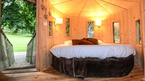 Una cama en una cabaña de madera con una cama grande. en Château de La Dame Blanche - Logis, en Geneuille