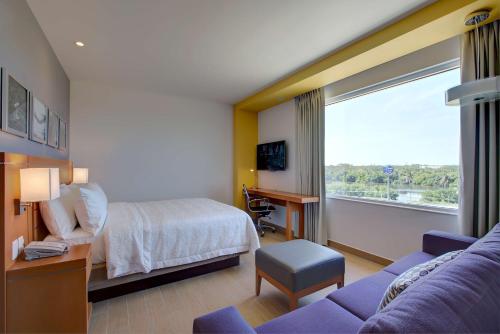 Hampton Inn & Suites by Hilton Paraiso في بارايسو: غرفه فندقيه بسرير واريكه