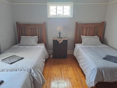 two twin beds in a room with a window at Blye Uitsig in Oudtshoorn