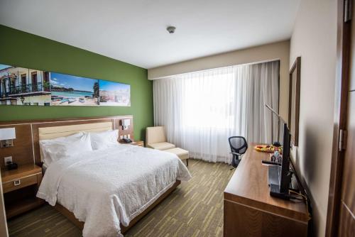 une chambre d'hôtel avec un lit et une télévision dans l'établissement Hampton By Hilton Santo Domingo Airport, à Boca Chica