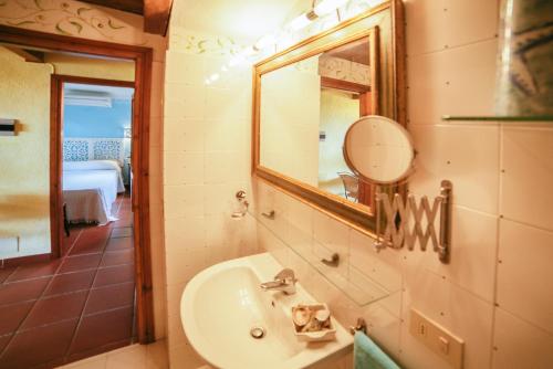 un baño con lavabo y espejo en Villaggio Cala Paradiso, en San Teodoro