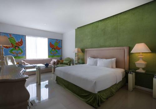 een slaapkamer met een groot bed en een groene muur bij Hilton MM Grand Hotel Puebla, Tapestry Collection in Puebla