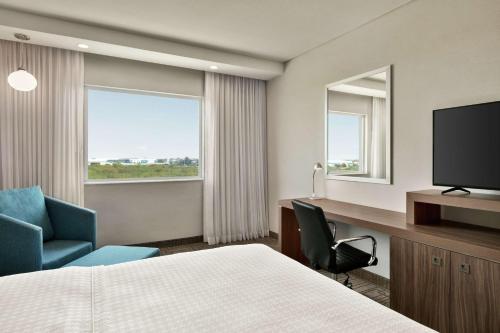 モンテレイにあるHampton Inn By Hilton Monterrey Apodacaのベッド、デスク、テレビが備わるホテルルームです。