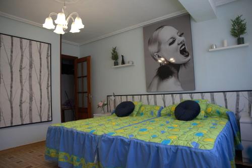 a bedroom with a bed with blue sheets and a picture on the wall at ApartamentoLillos in Luanco