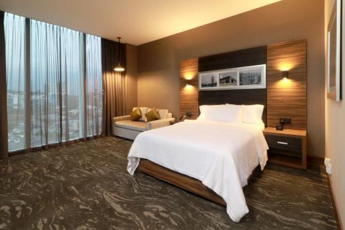 a hotel room with a large bed and a couch at Hilton Garden Inn Monterrey Obispado in Monterrey