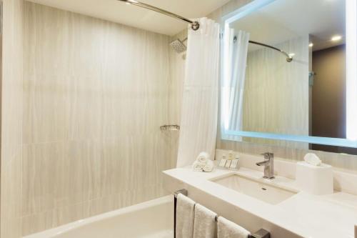 ein Badezimmer mit einem Waschbecken, einer Badewanne und einem Spiegel in der Unterkunft Hilton Garden Inn Salamanca in Salamanca
