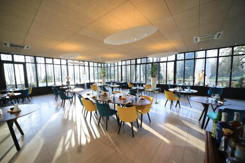 une salle à manger avec tables, chaises et fenêtres dans l'établissement Château de La Dame Blanche - Logis, à Geneuille