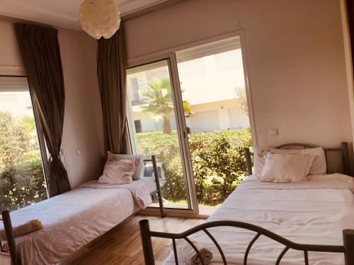two beds in a room with a large window at Hébergement bord de mer in Casablanca