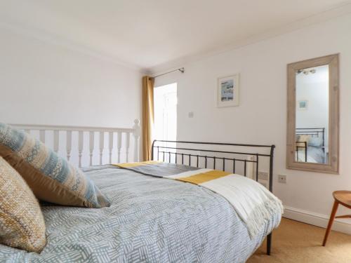 1 dormitorio con cama, espejo y silla en Flintstone Cottage en Penzance
