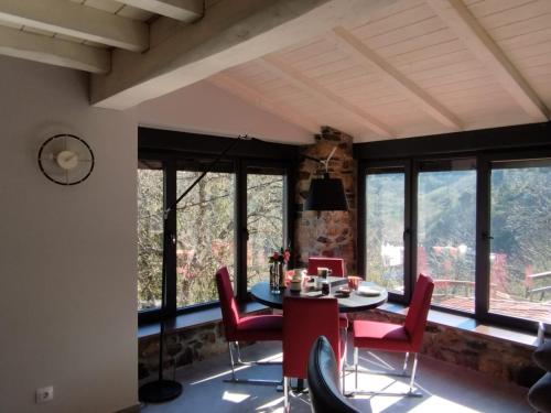 Un comedor con mesa y sillas y ventanas. en Casa Yañez, en Chantada