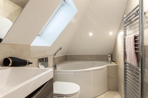 La salle de bains est pourvue d'une baignoire, de toilettes et d'une lucarne. dans l'établissement Beautiful 2-Bed Apartment in London, à Londres