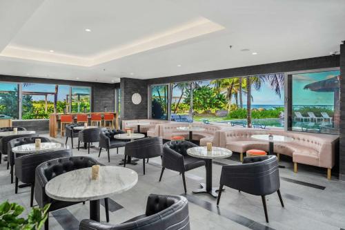 um restaurante com mesas e cadeiras e janelas grandes em Koi Resort Saint Kitts, Curio Collection by Hilton em Basseterre