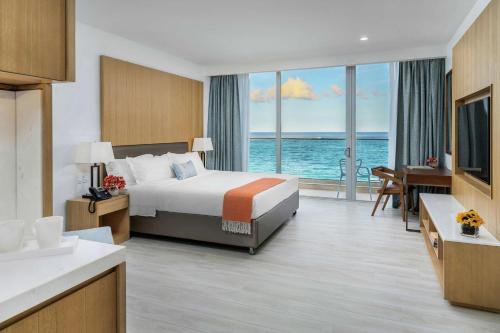 a hotel room with a bed and a view of the ocean at Koi Resort Saint Kitts, Curio Collection by Hilton in Basse Terre Town