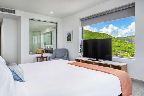 a white bedroom with a large window and a television at Koi Resort Saint Kitts, Curio Collection by Hilton in Basse Terre Town