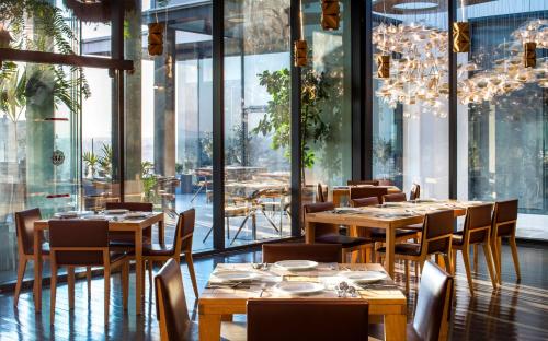 a restaurant with wooden tables and chairs and windows at Hilton DoubleTree Guadalajara Centro Historico in Guadalajara