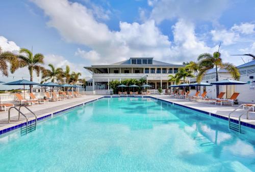 a large swimming pool with chairs and a building at Mahogany Bay Resort and Beach Club, Curio Collection in San Pedro