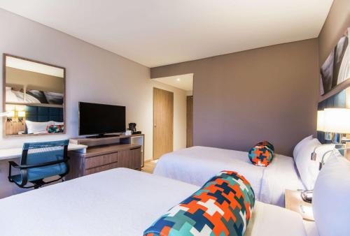 a hotel room with two beds and a flat screen tv at Hampton By Hilton Cucuta in Cúcuta