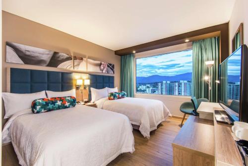 库库塔Hampton By Hilton Cucuta的有两张床和一扇大窗户的酒店房间