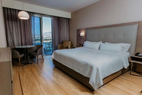 a hotel room with a large bed and a table at Hilton Garden Inn Silao Aeropuerto Bajio in Silao