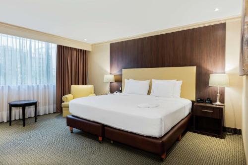 a hotel room with a large bed and a chair at Hilton Mexico City Airport in Mexico City