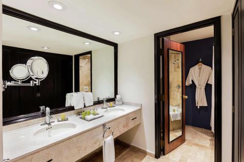 La salle de bains est pourvue d'un lavabo et d'un grand miroir. dans l'établissement Hilton Mexico City Airport, à Mexico