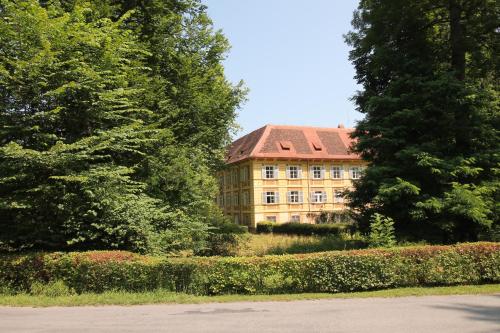 a building with a red roof in the middle of trees at Schloss Frauenthal in Deutschlandsberg