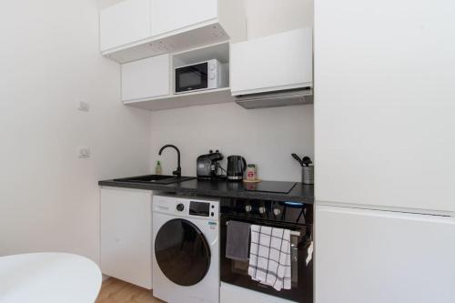une cuisine avec un lave-linge et un micro-ondes dans l'établissement Confort Climatisé et Suite Privée en Sousplex, à Montpellier