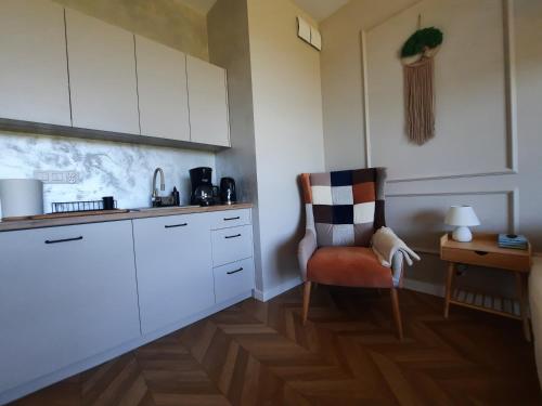 une cuisine avec des placards blancs, une chaise et une table dans l'établissement Ukiel Park Apartament Kozetka, à Olsztyn