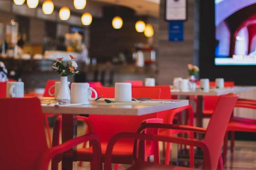 a restaurant with red chairs and tables with flowers on them at Hilton Garden Inn Leon Poliforum in León