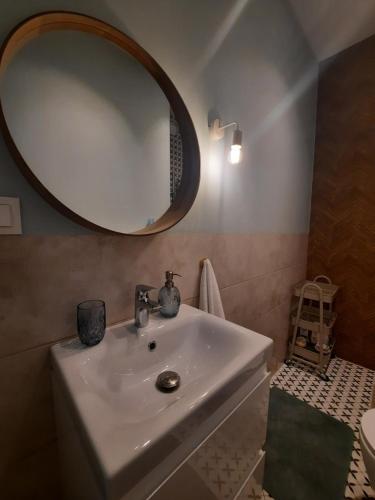 a bathroom with a white sink and a mirror at Ukiel Park Apartament Kozetka in Olsztyn