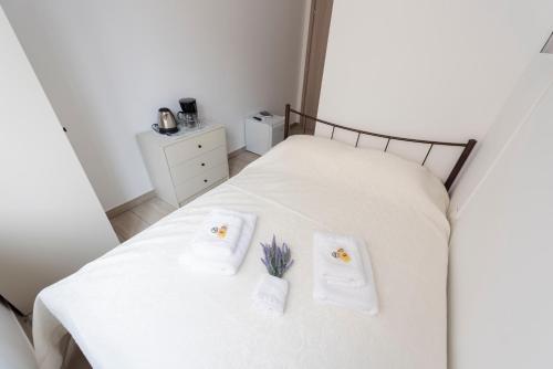 a white bed with two towels with flowers on it at ATHENS COMMERCIAL in Athens