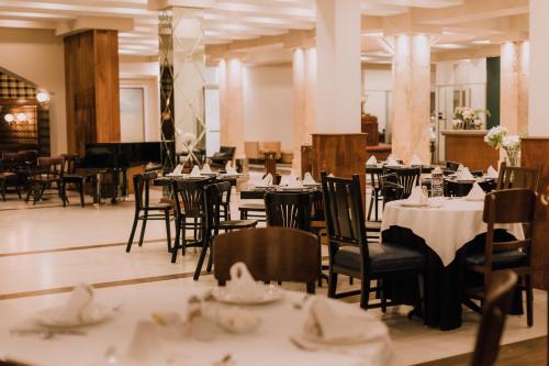 un comedor con mesas, sillas y un piano en Hotel Leon, en León