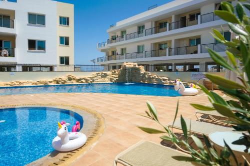 a swimming pool with two inflatable swans in a hotel at SEABREEZE APARTMENT 200m away from the sea in Paralimni
