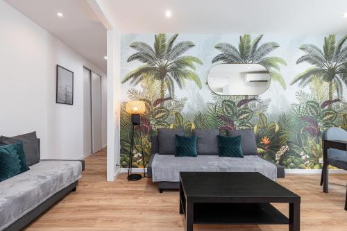 - un salon avec un canapé et une fresque murale de palmiers dans l'établissement LA CASA REINE JEANNE- CENTRAL prés de la gare - WIFI - PARKING - Neuf ET CONFORT, à Nice