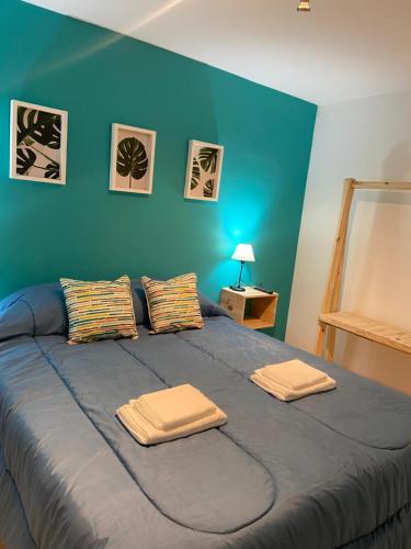 Un dormitorio azul con una cama grande con toallas. en Padre Vázquez Apartment en Maipú