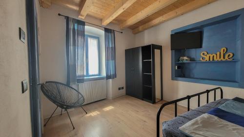 Schlafzimmer mit einem Bett, einem TV und einem Stuhl in der Unterkunft Maison AnnaBelle in Ceniga