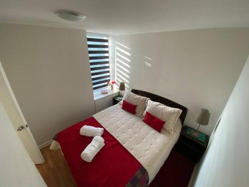um quarto com uma cama com almofadas vermelhas e brancas em Hermoso Departamento aire acondicionado, Internet em Talca