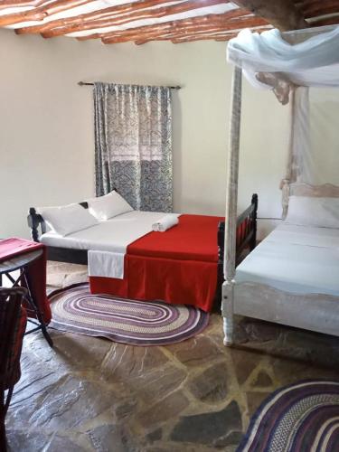 a bedroom with two beds and a red blanket at Alooma Studio homes in Galu