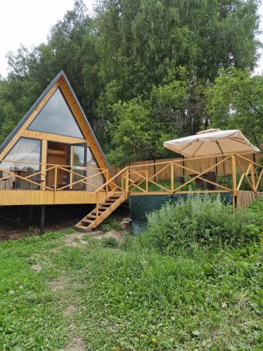 a small house with a deck and an umbrella at Eywa House in Kamenskoye Plato