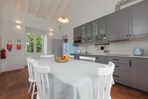 a kitchen with a table and white cabinets and a table and chairs at Jardim das Camélias in Madalena