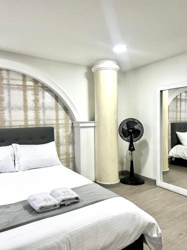 a white bedroom with a bed and a mirror at Orbe Hotel Medellín in Medellín