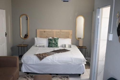 a bedroom with a large white bed with two mirrors at Unitrainview guest house in Pretoria