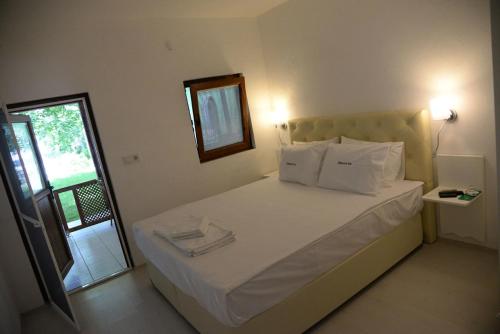 a bedroom with a bed with white sheets and a mirror at Chiyanno's Inn in Dalyanköy