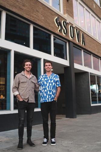 two men are standing in front of a building at SOVA Micro-Room & Social Hotel in Dallas