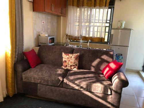 a couch in a kitchen with red pillows on it at Tom Mboya Estate - Fast WI-FI, Netflix and Parking 1Br Apartment in Kisumu Town in Kisumu