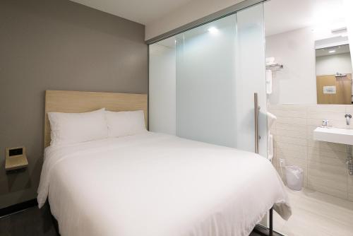 a bedroom with a white bed and a bathroom at SOVA Micro-Room & Social Hotel in Dallas
